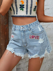Women's distressed denim shorts with buttons, pockets, and raw hems.