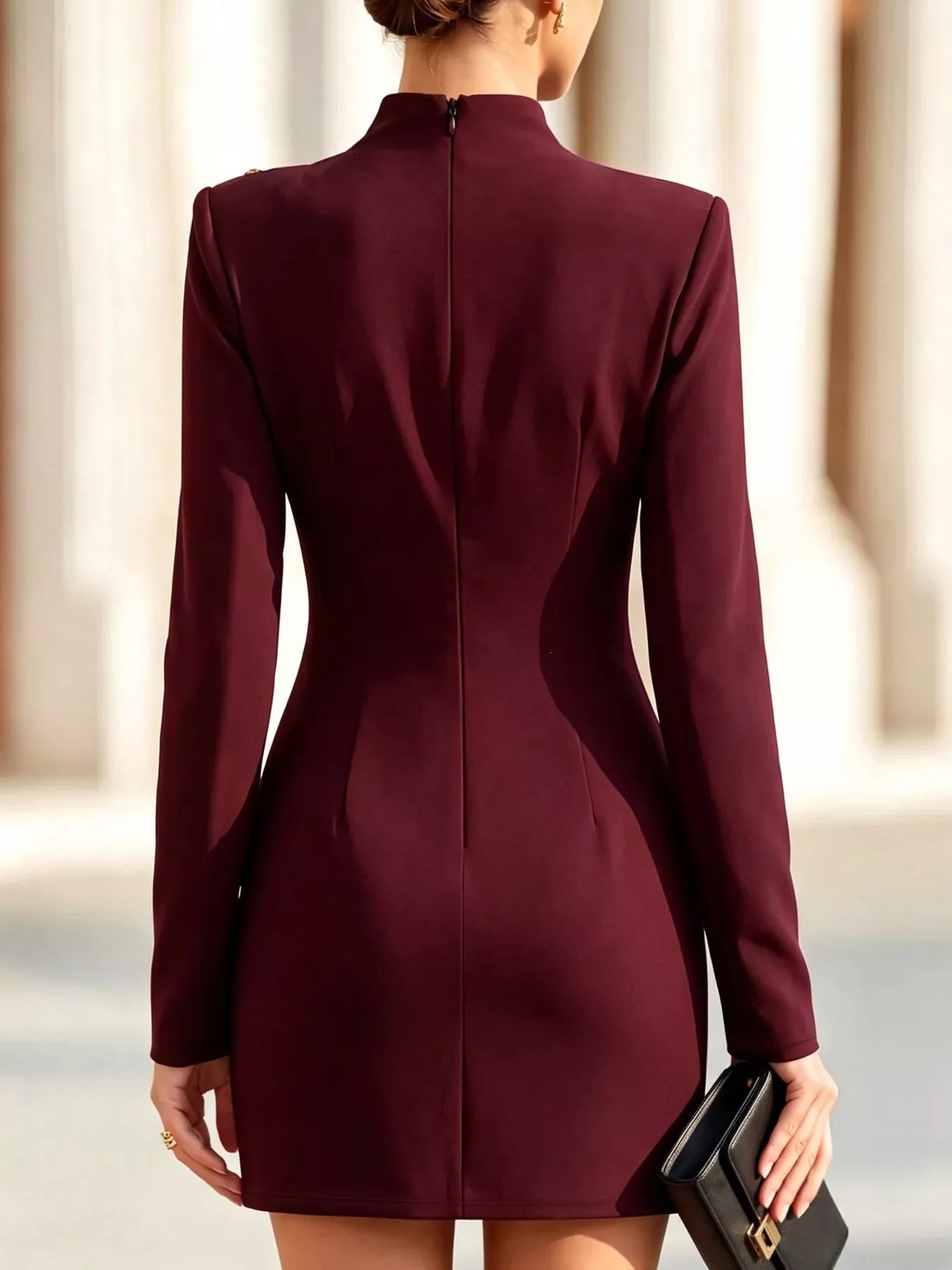 Back view of model outdoors wearing burgundy mock neck mini dress with long sleeves and back zip