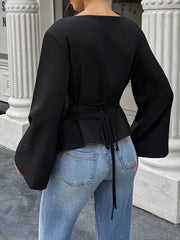 Back view of black boat neck long sleeve top with waist ties and flared sleeves on model