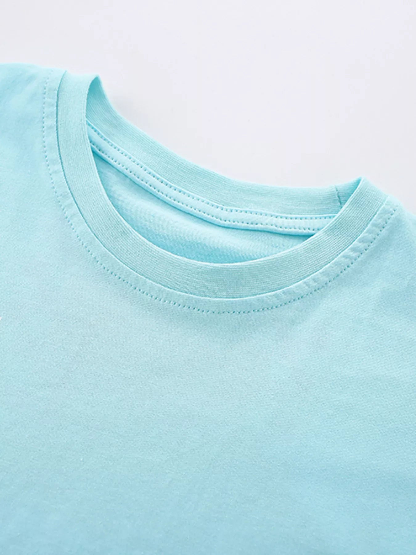 Close-up of the ribbed round neckline and stitching on a mint blue children's T-shirt