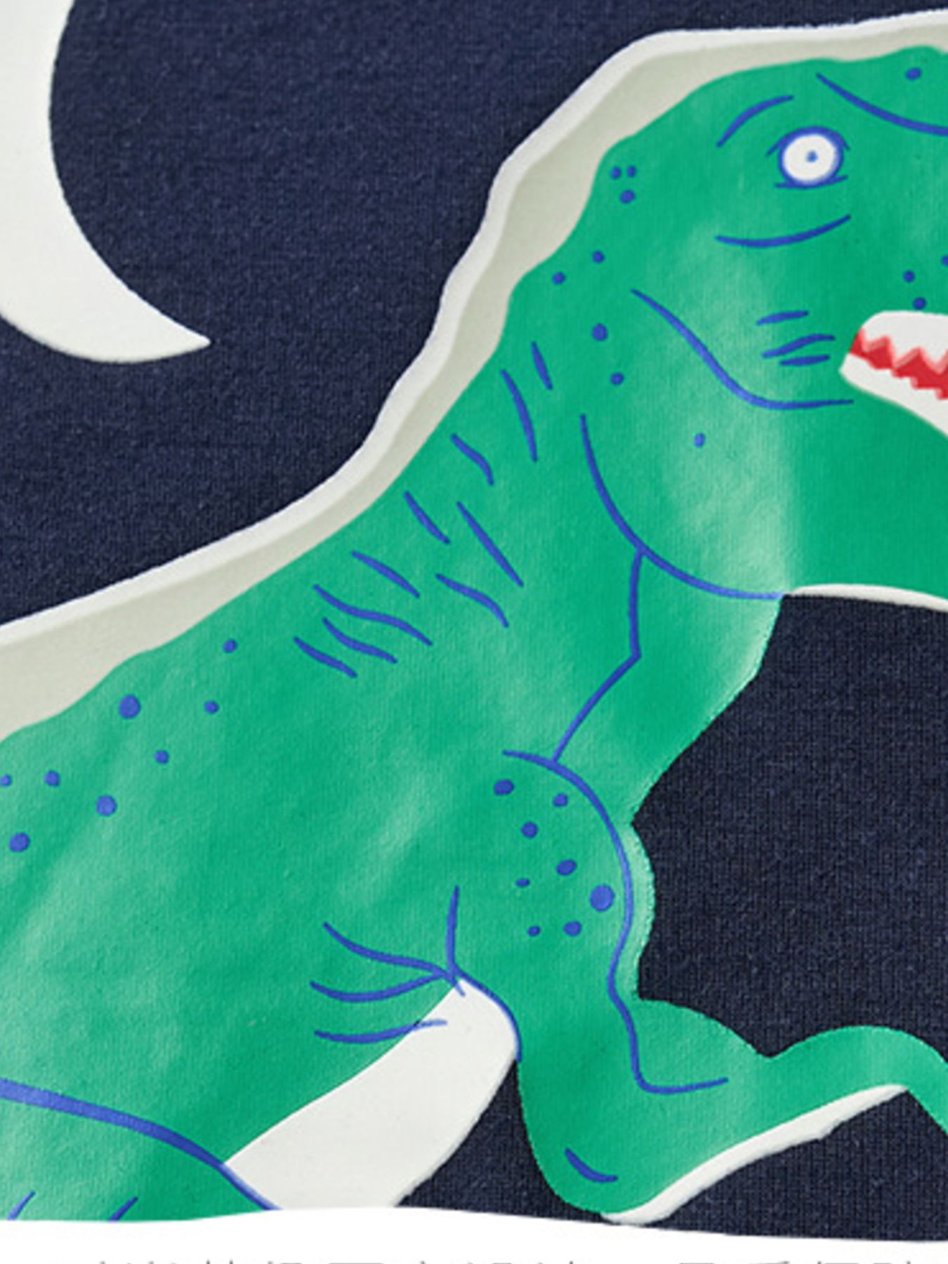 Close-up detail of the green dinosaur graphic and crescent moon on the navy tee