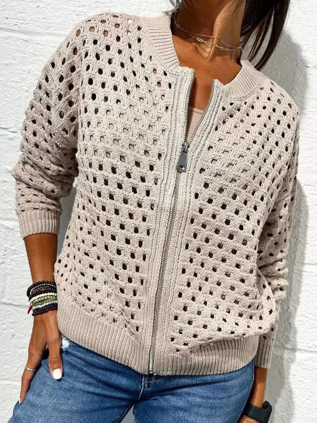 Front view of a pale beige openwork crochet cardigan with a front zip