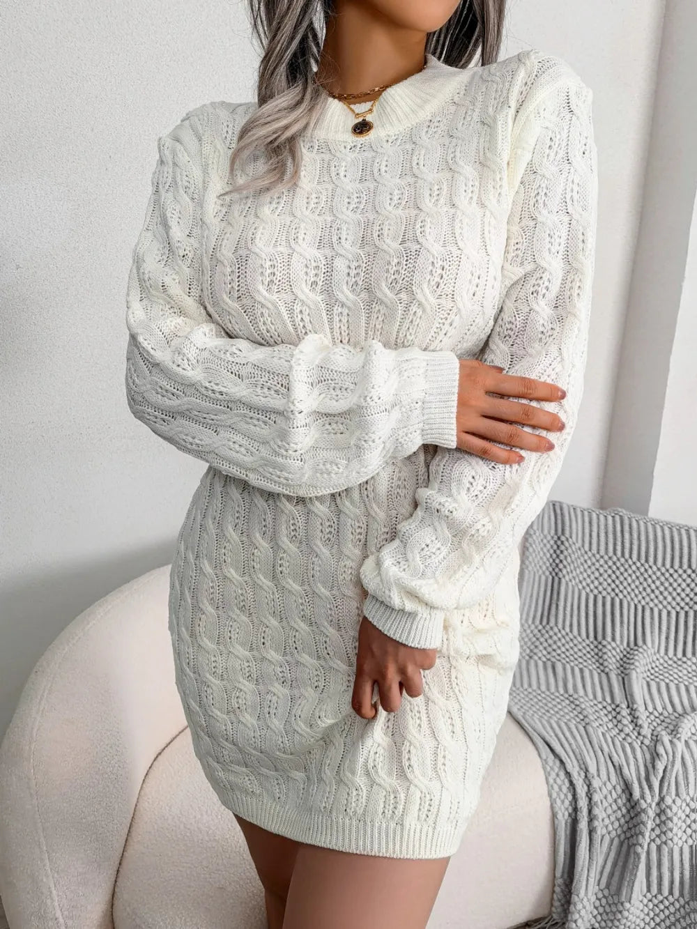 Women's white cable-knit mini wrap sweater dress with a round neckline.