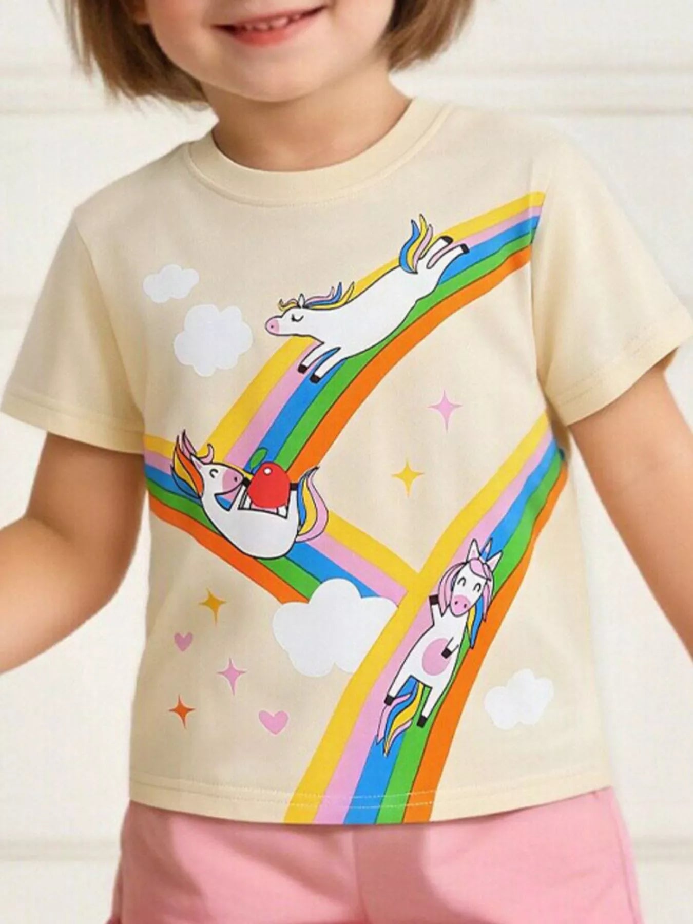 Children's cream round-neck T-shirt featuring a rainbow unicorn graphic.