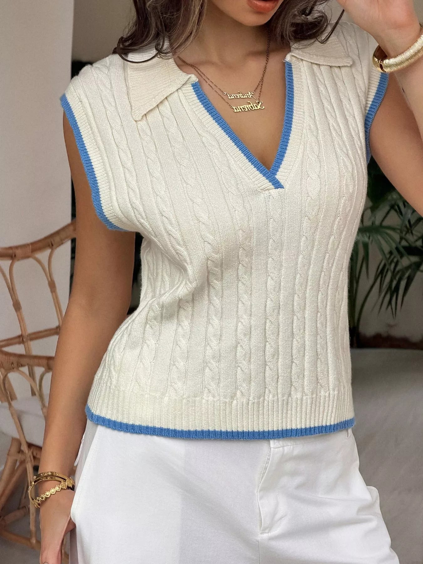 Front view of the cream cable knit vest with blue trim at the neckline and hem