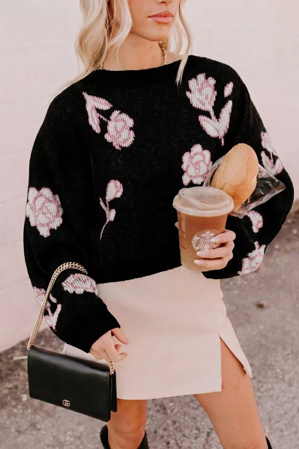 Angled front view of black floral pullover sweater with pink roses and puff sleeves
