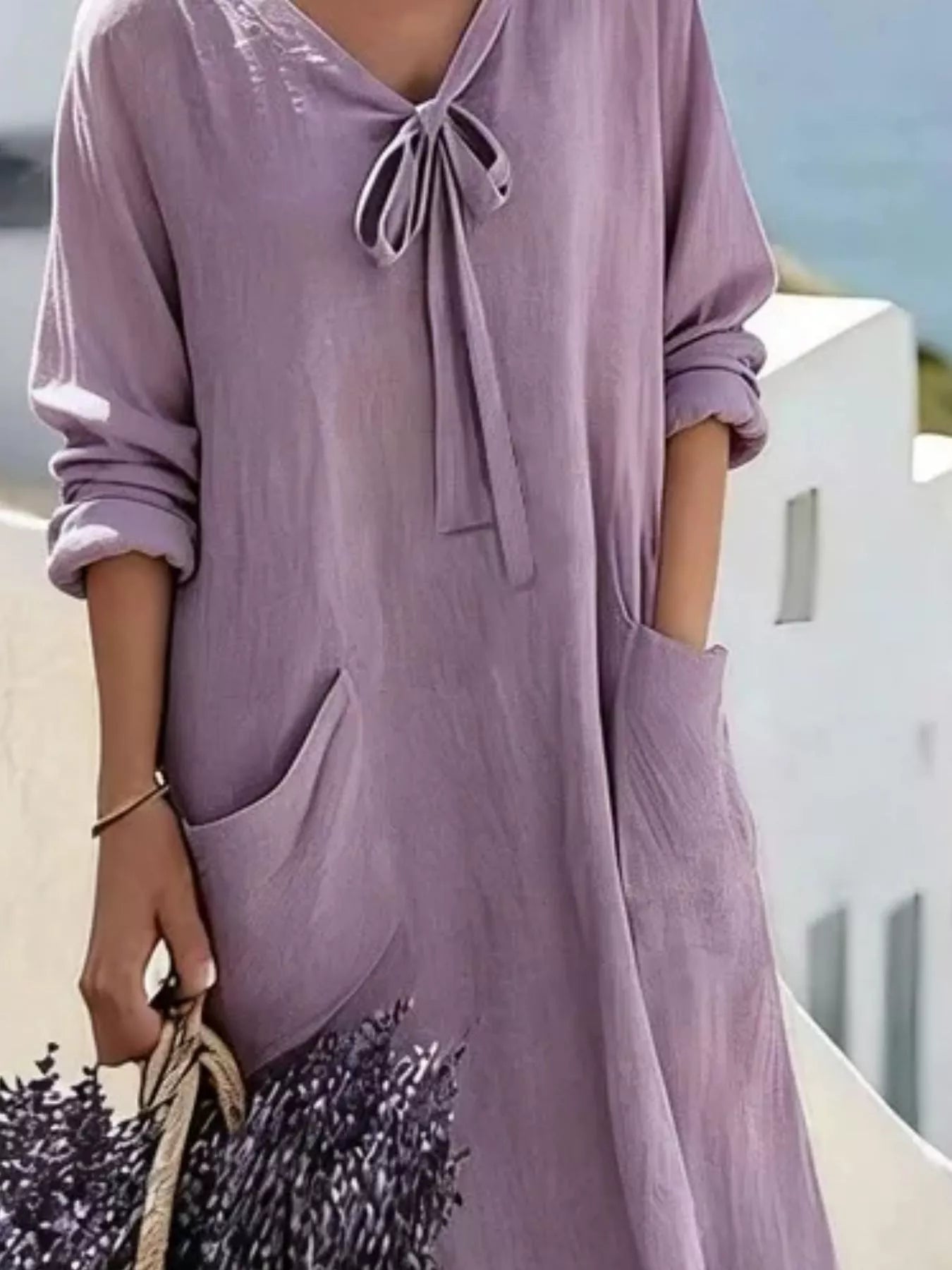 Cropped front view of light purple long sleeve loose maxi dress, showing tie neck and large pockets