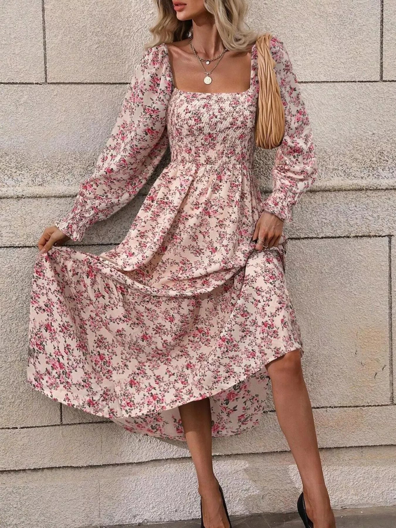 Pink floral midi dress with long puff sleeves, model lifting the flowing skirt