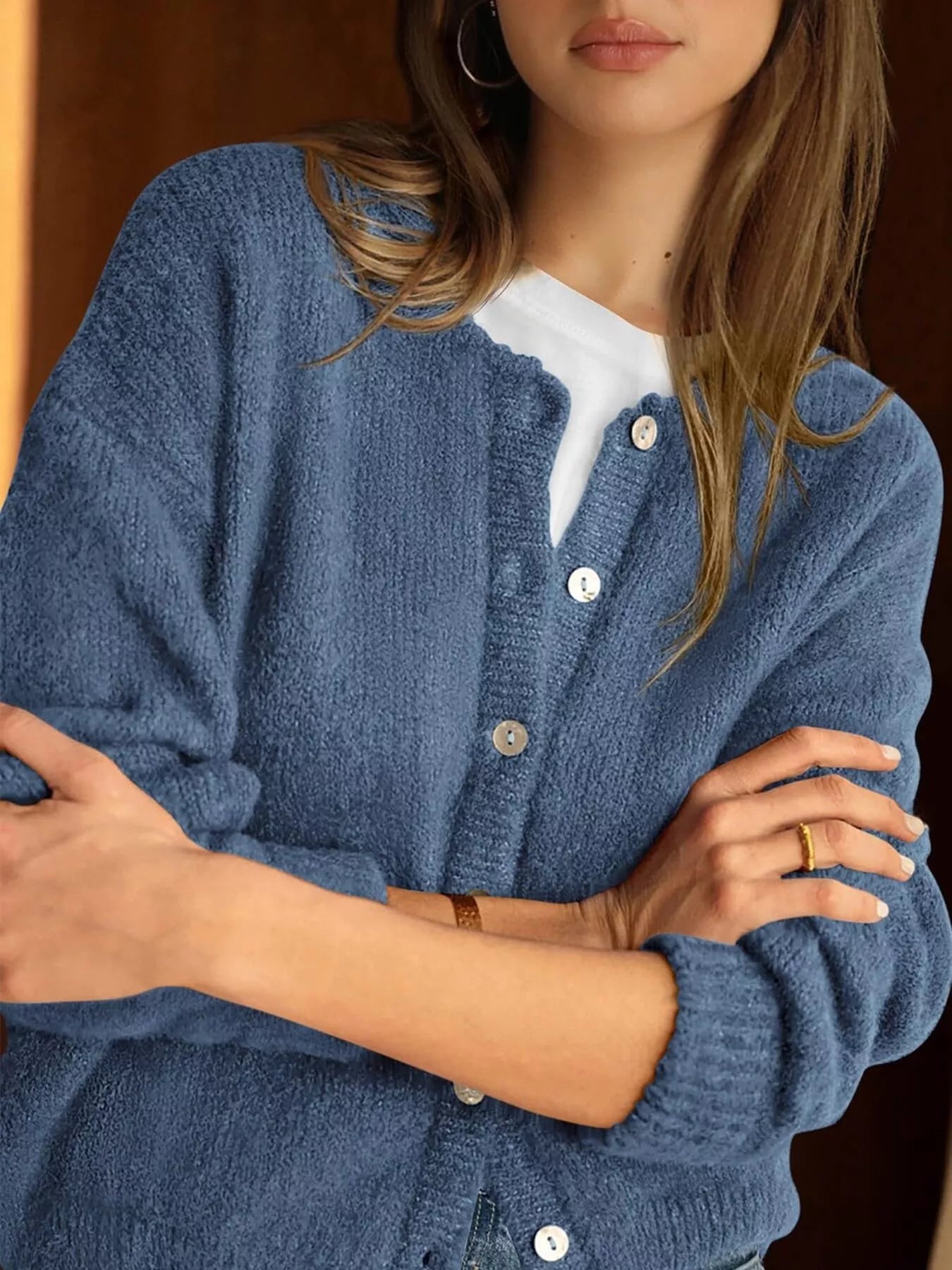 Close up of haze blue button down cardigan with white buttons worn over a white top
