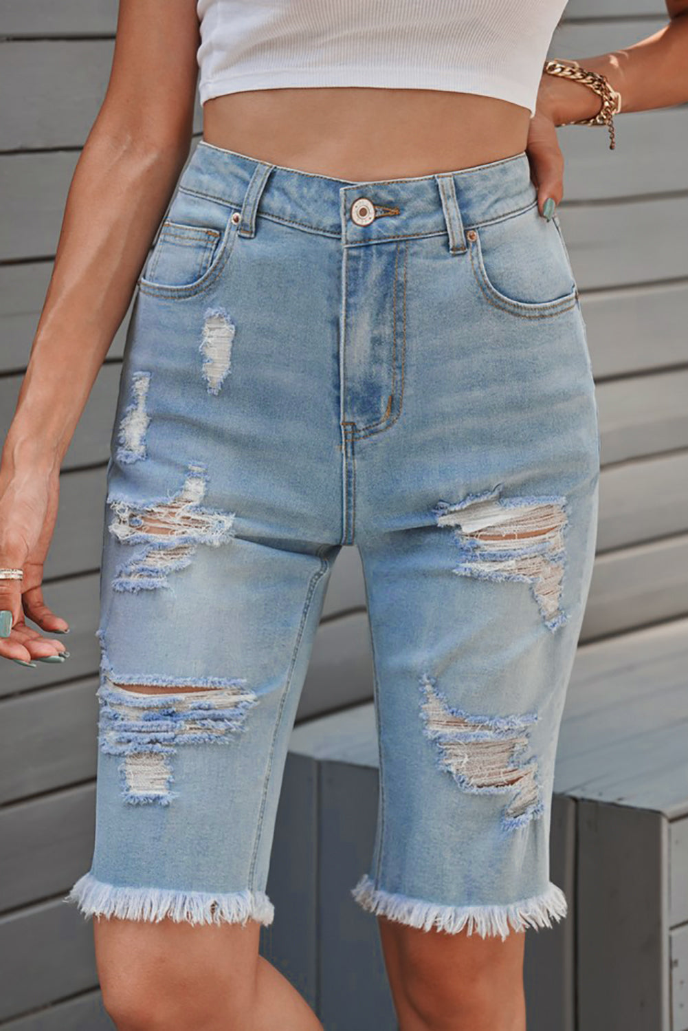 Women's long Bermuda shorts with distressed detailing and raw hems.