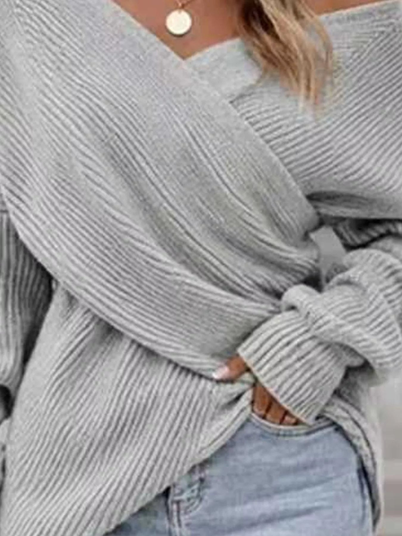 Close front view of gray ribbed knit sweater showing crisscross V neckline detail.