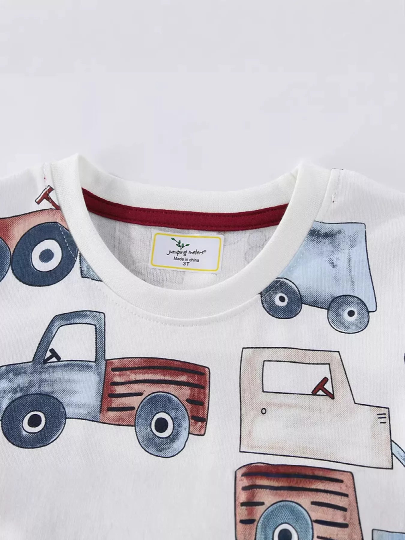 Close up of white children's t-shirt round neckline with red inner trim and truck print