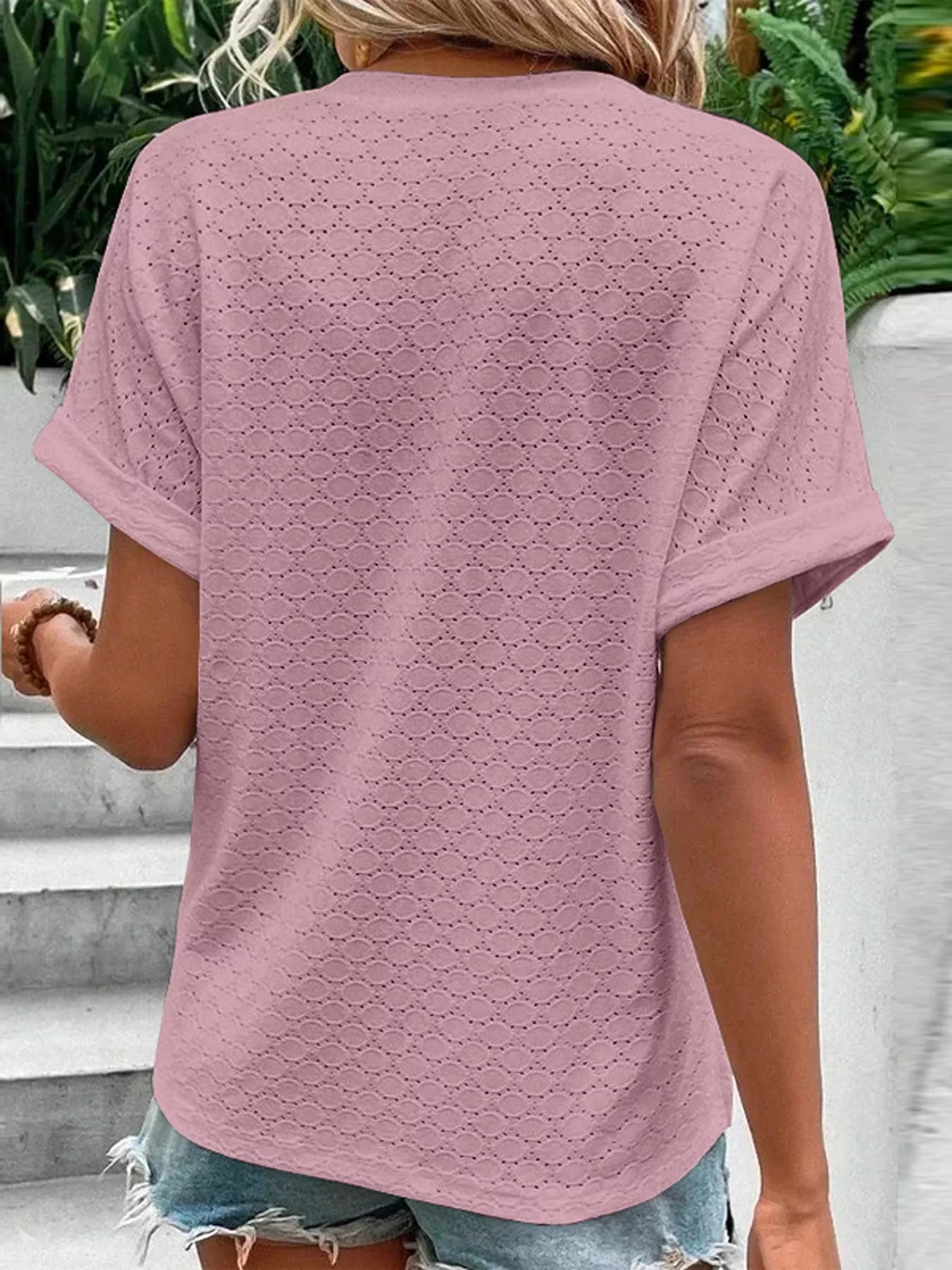 Back view of a mauve short-sleeve top featuring a subtle eyelet pattern and notched neckline.
