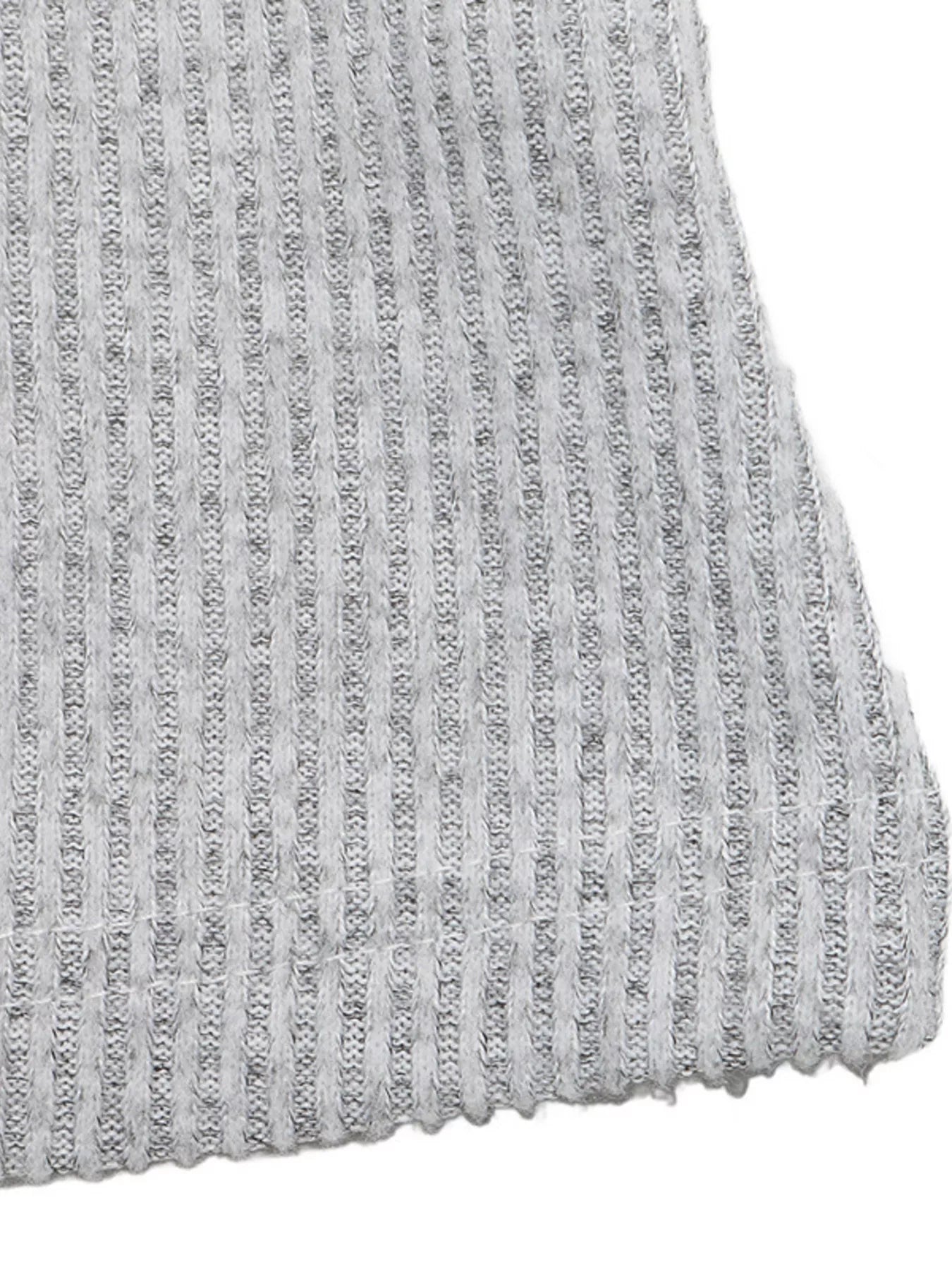 Close-up detail of light gray ribbed knit fabric with vertical lace-textured stripes and scalloped hem edge