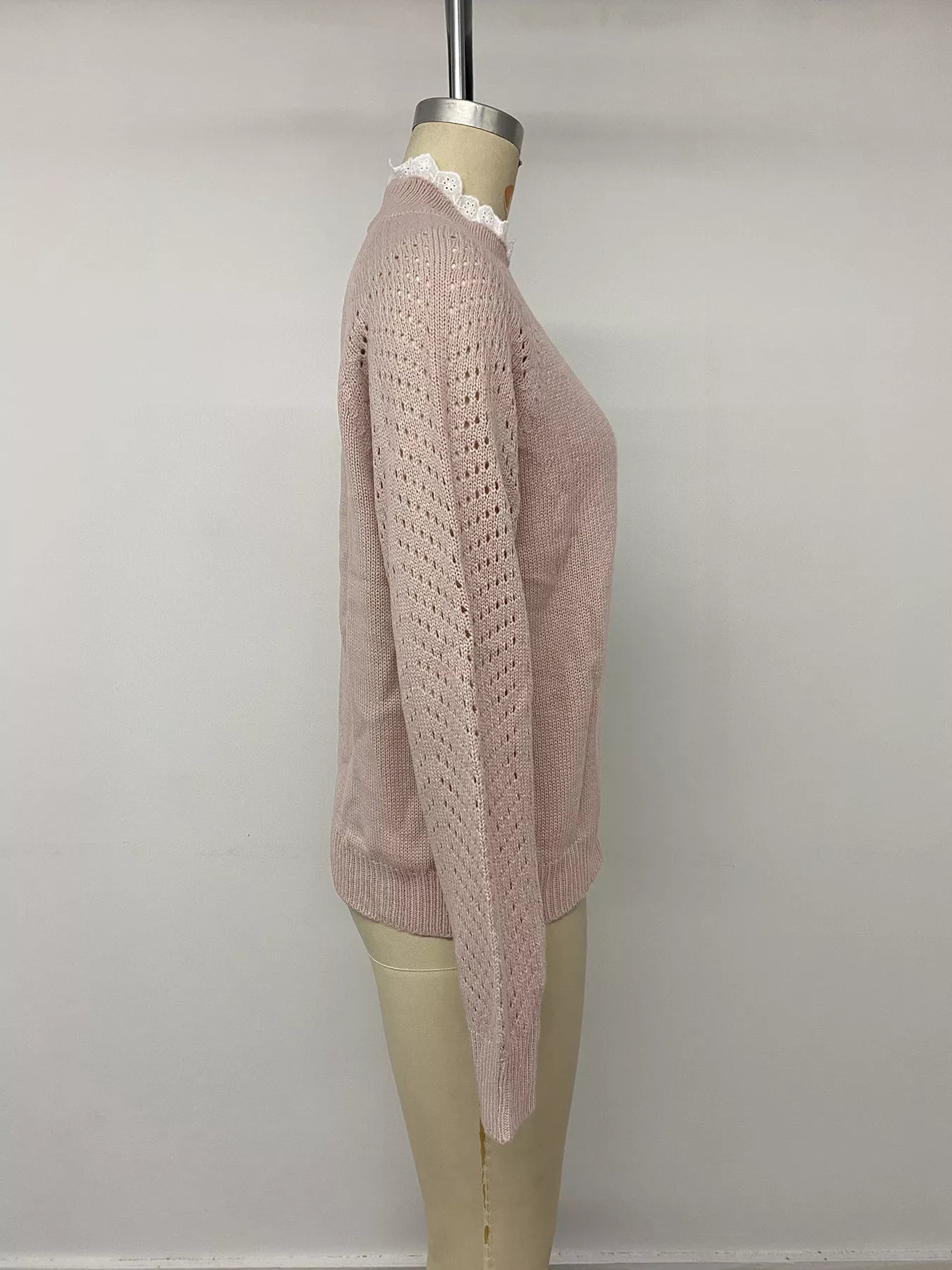 Side view on a mannequin of a pink sweater with openwork long sleeves and lace collar