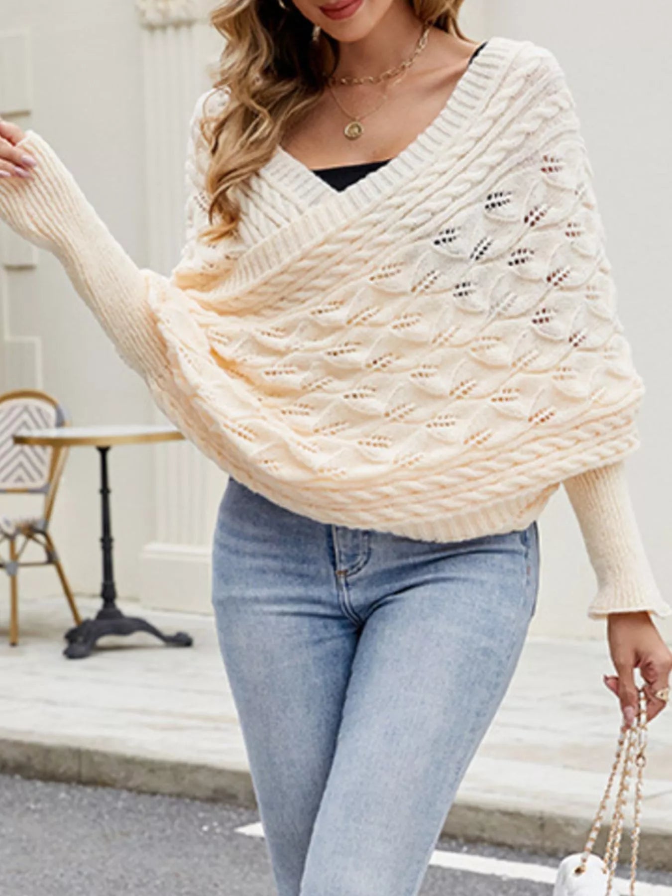 Front view of cream cable knit batwing sweater with V neckline and leaf pattern.