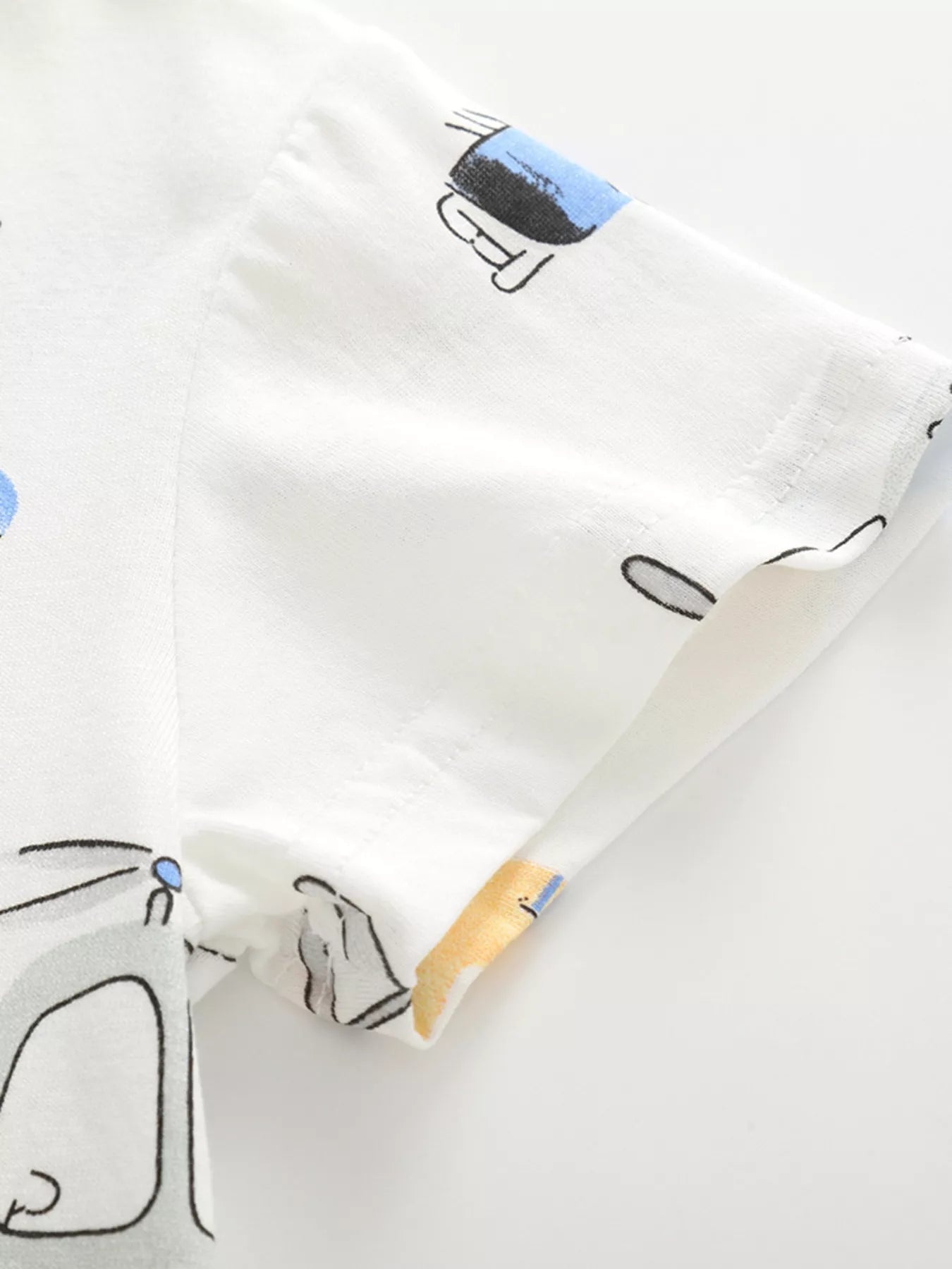 Close-up of the white cotton sleeve and hem stitching with a partial vehicle print