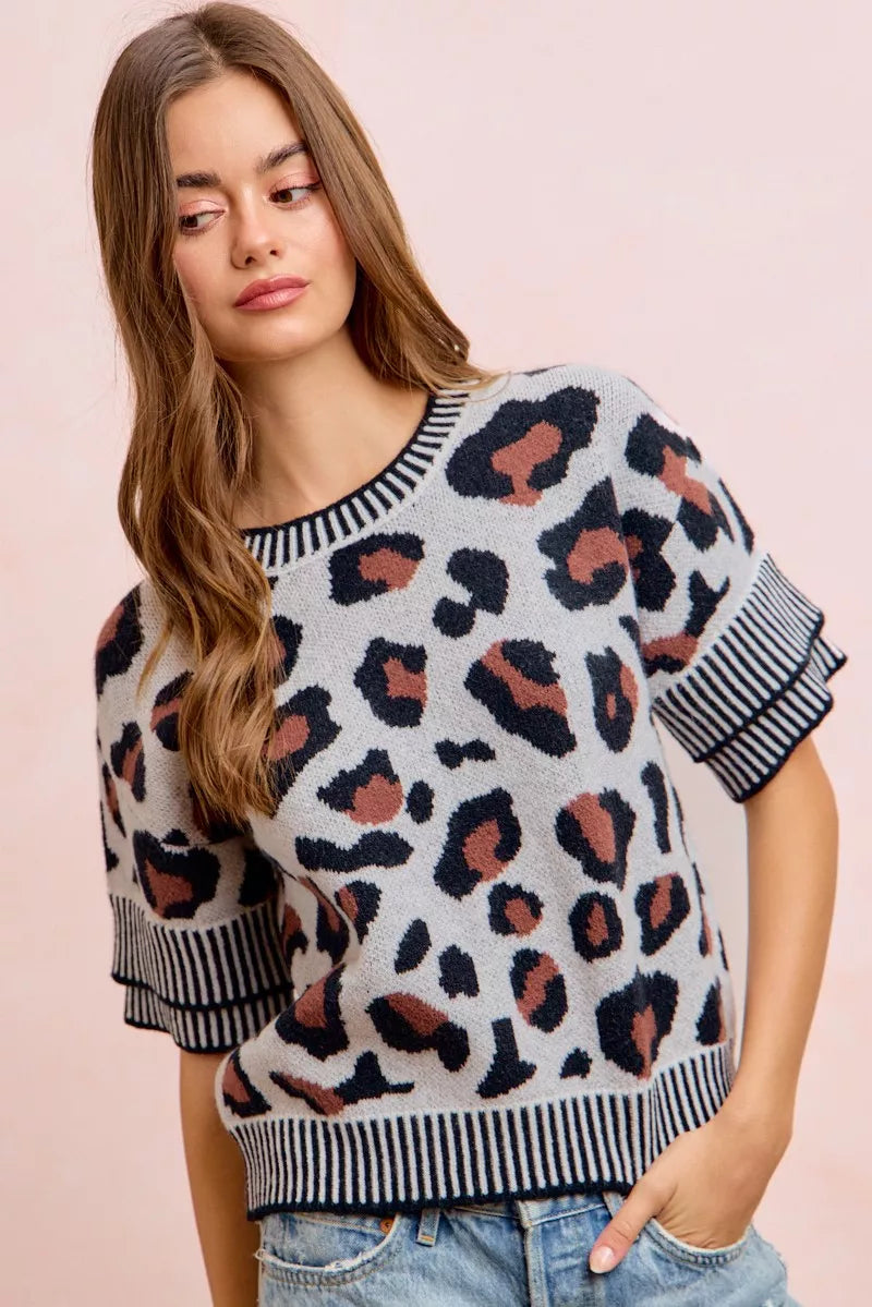 Side front view of a light gray leopard print knit top with striped trim.