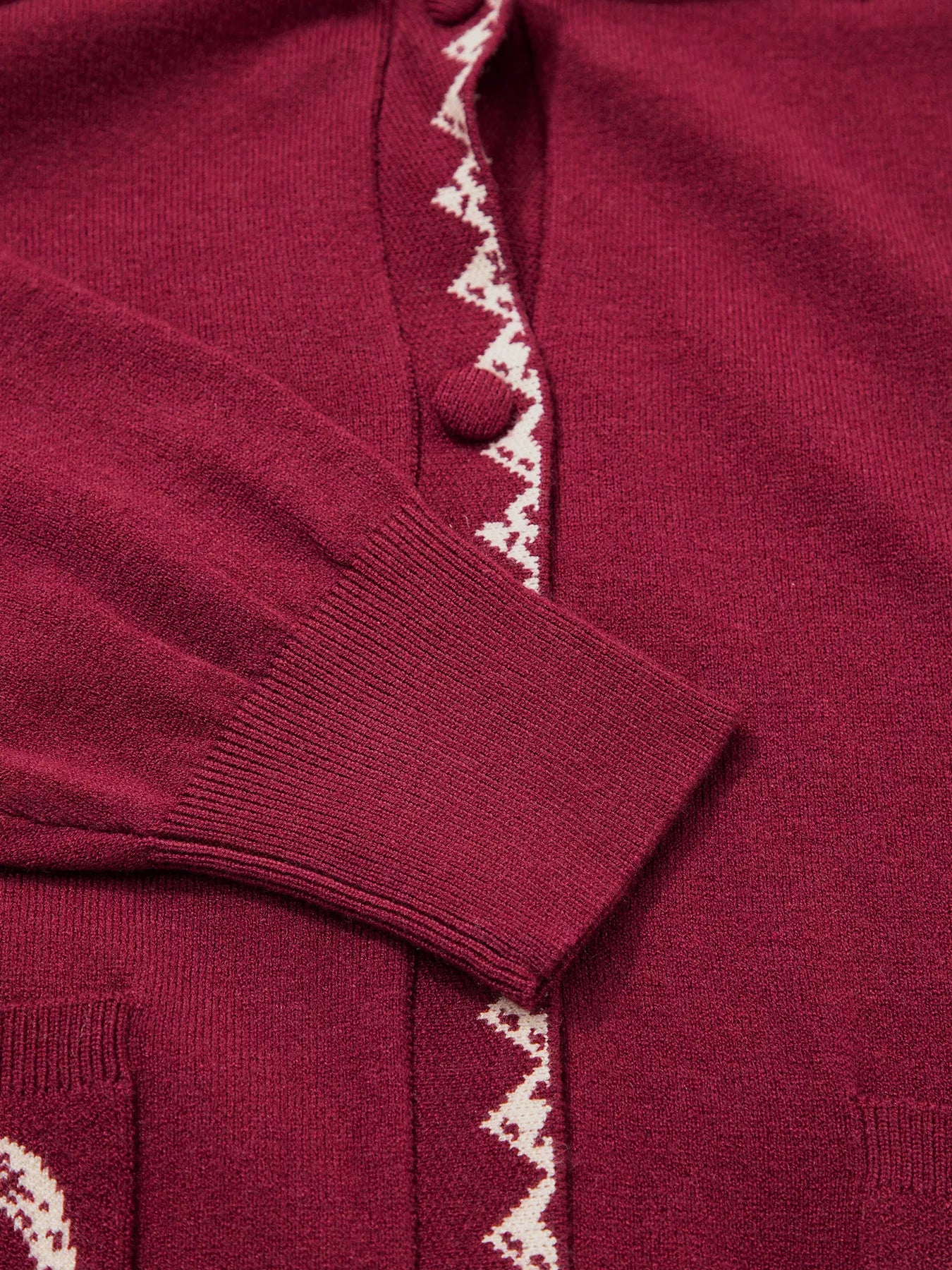 Close view of the burgundy cardigan button placket zigzag trim and cuff