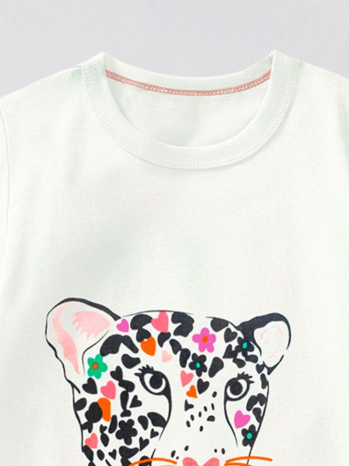 Close-up of the white round neckline above the top of the leopard print