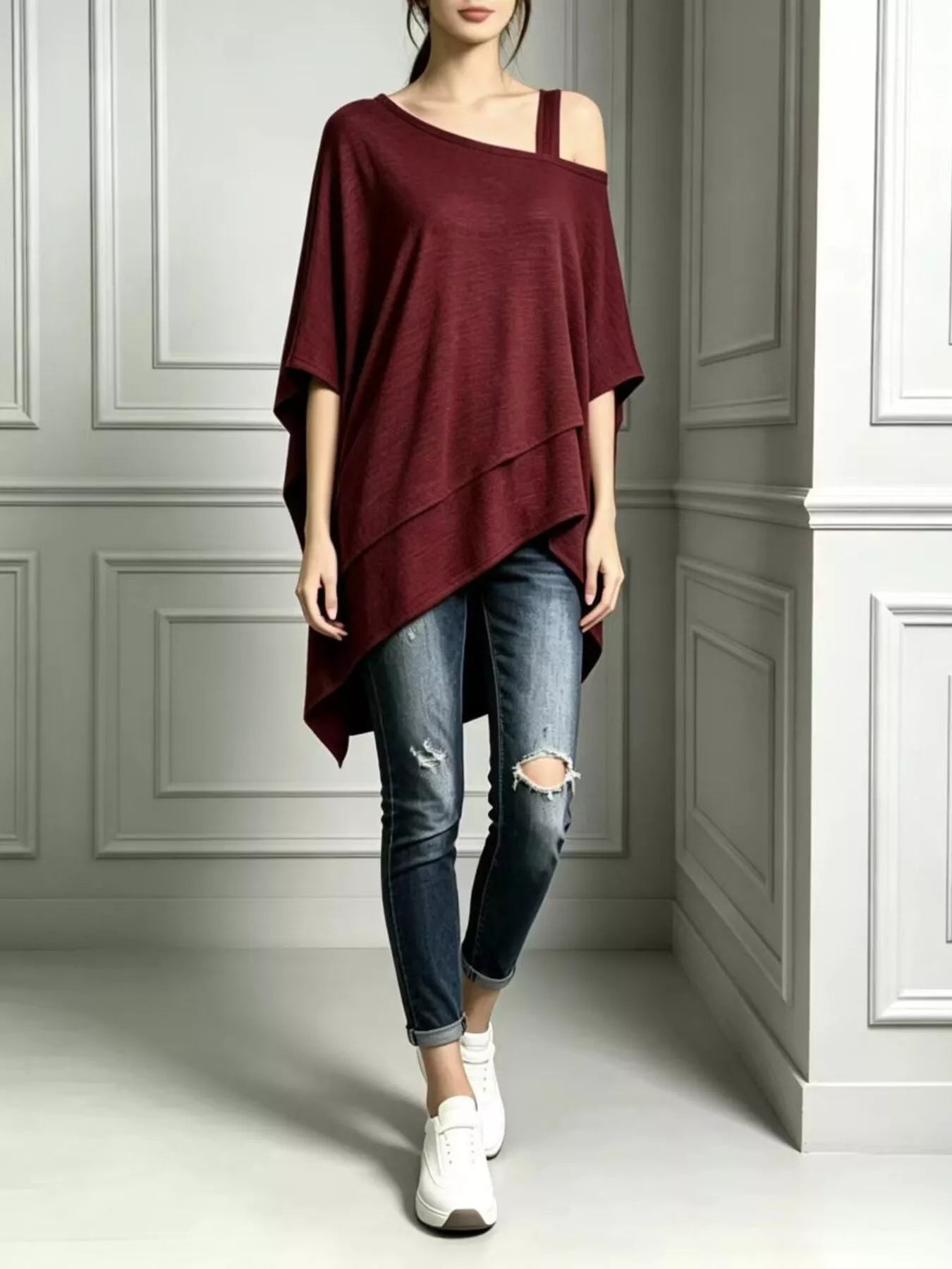 Burgundy women's asymmetrical-neck short-sleeve tunic top modeled with cuffed jeans and white sneakers