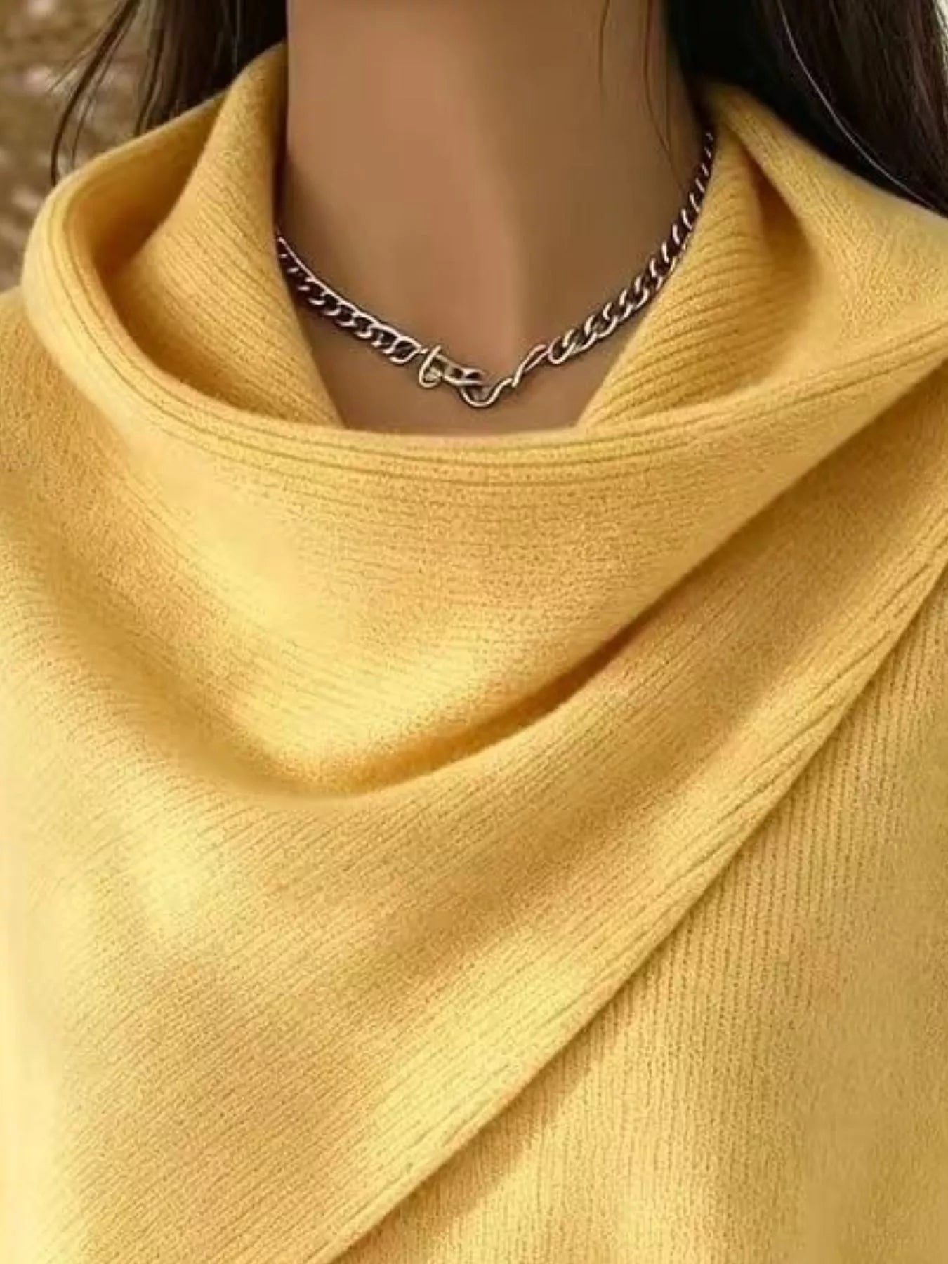Close-up of the yellow cowl neckline showing the draped asymmetric collar and fine knit texture
