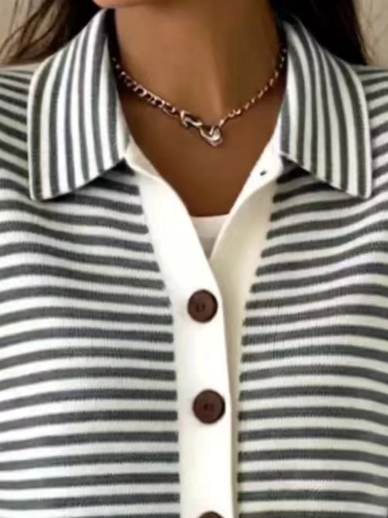 Close-up of the collar and brown buttons on a black and white striped knit cardigan