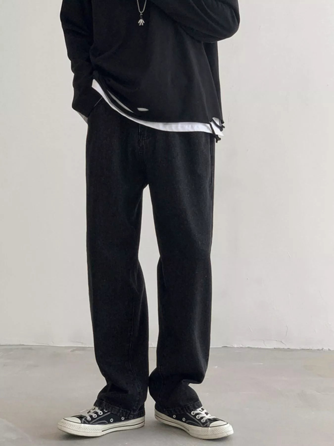Men's Black loose fit wash jeans on model, front view with black top.