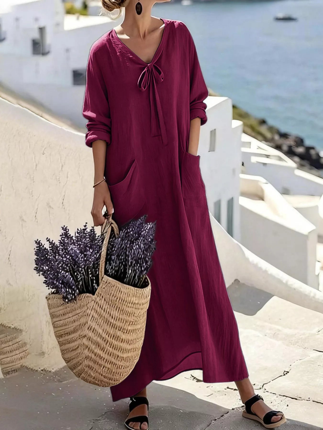 Model wearing plum purple long sleeve loose maxi dress outdoors, full view with large pockets and tie neck