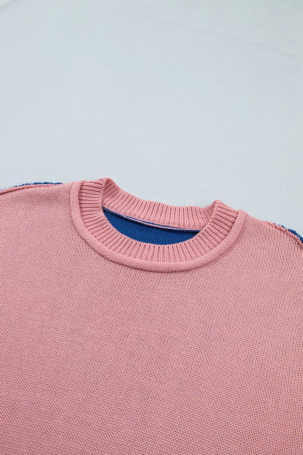 Close up of the pink sweater front neckline with ribbed trim and blue lining
