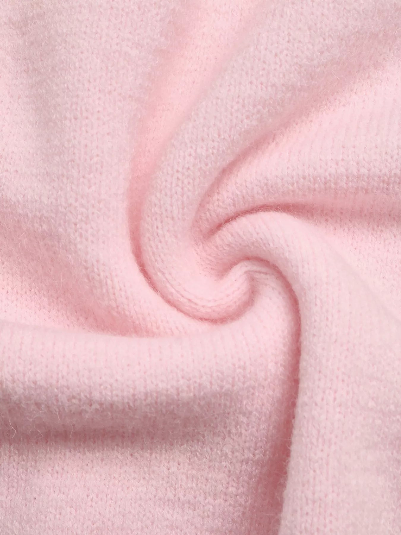 Close-up of soft pink knit fabric with a gentle twist showing its fuzzy texture