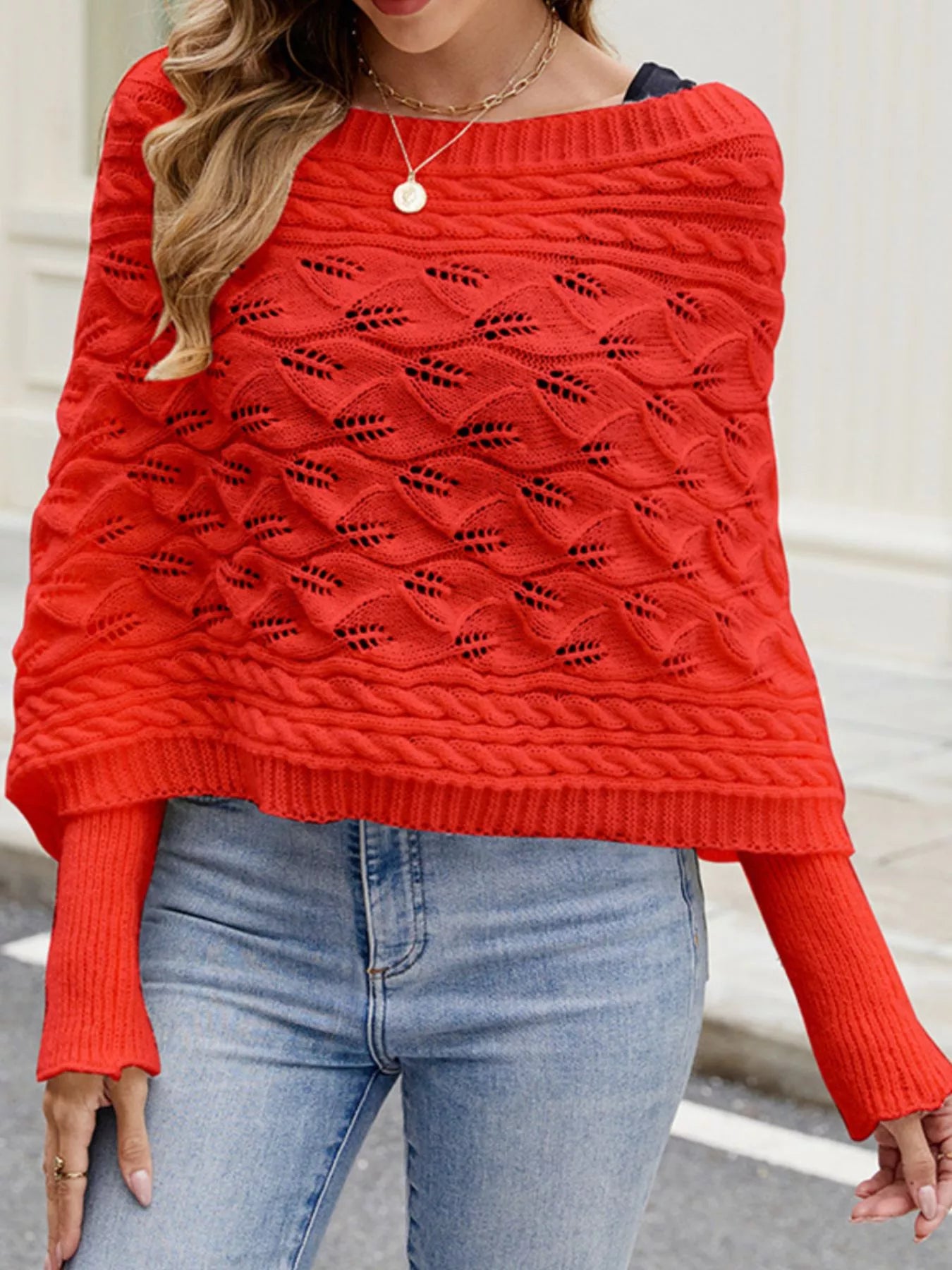 Front view of red batwing sweater with wide neckline and cable knit texture.