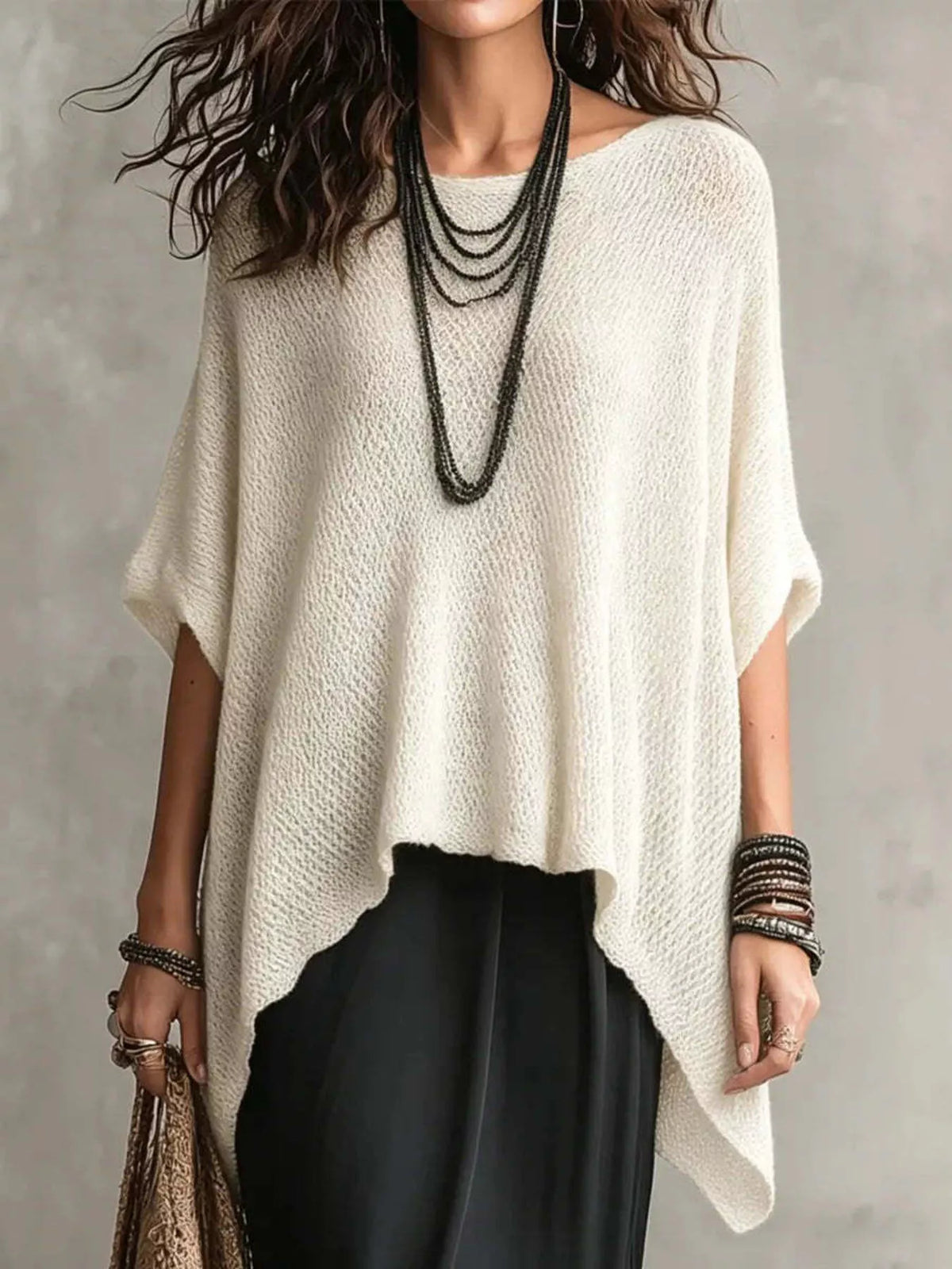 Front view of a loose white open knit cover-up with an asymmetrical pointed hem