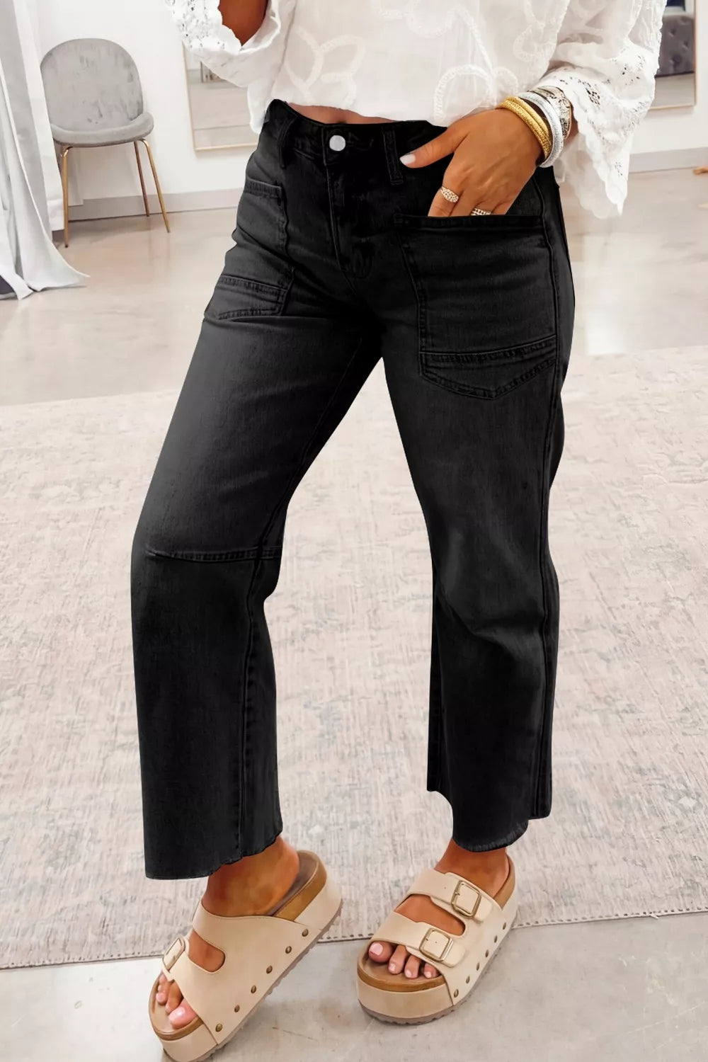 Women's black cropped straight-leg jeans with frayed hems and pockets.