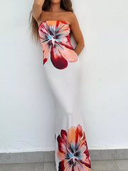 Strapless bodycon maxi dress with large floral print worn against a white wall, arm raised
