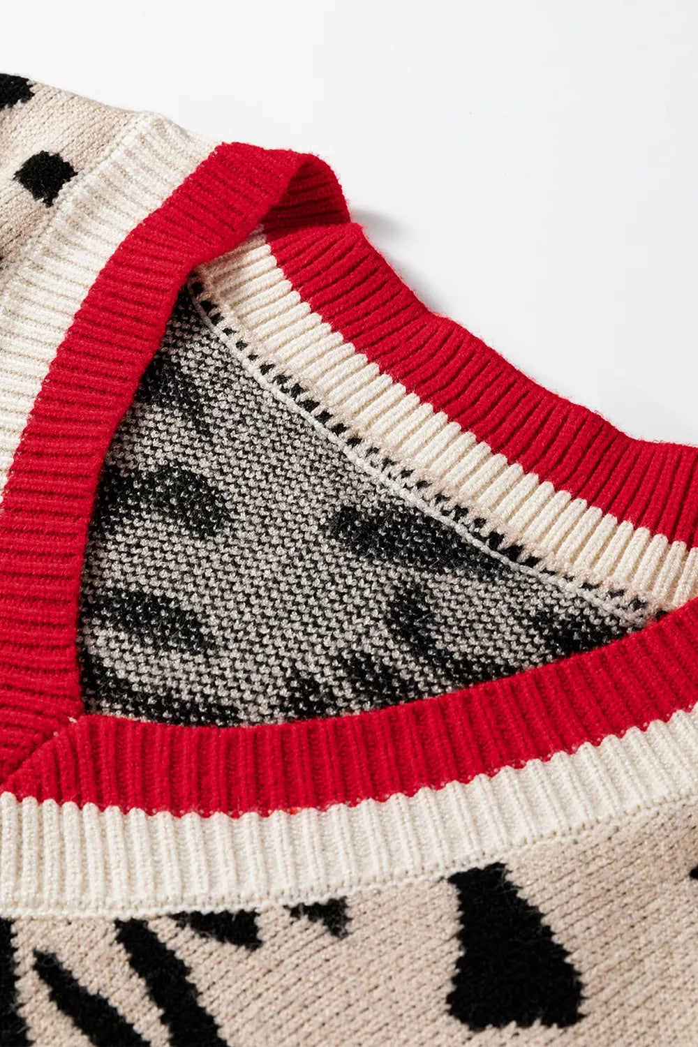 Close view of red and cream ribbed V neck trim on a leopard print sweater.