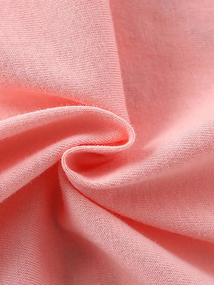 Close-up of soft blush pink fabric texture of children's t-shirt, gathered in folds