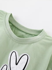 Close view of the round neckline and top of the white heart applique on the sage T-shirt