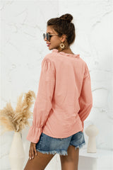Back view of a coral pink frill-trim shirt with long flounce sleeves, modeled with denim shorts