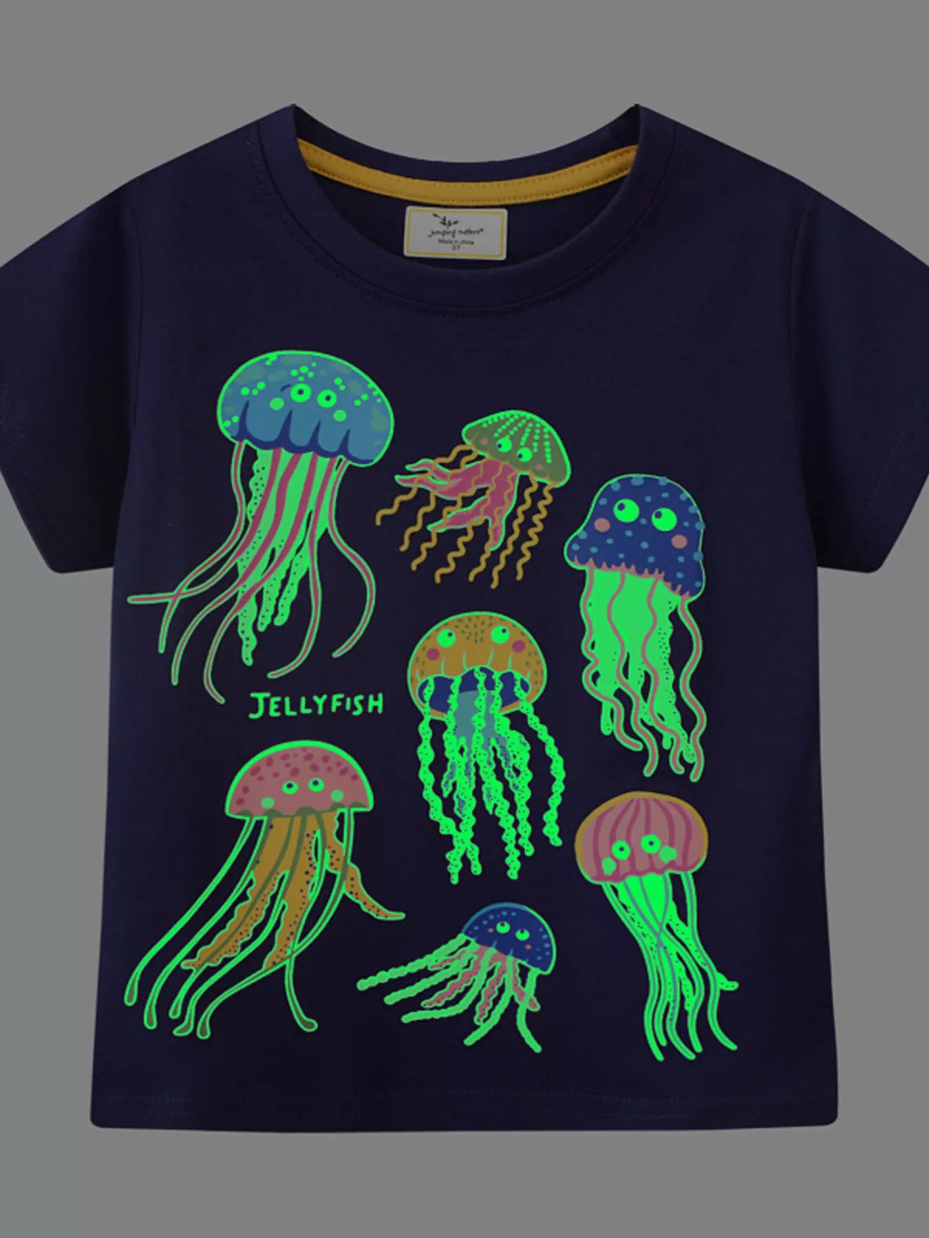 Front view of black children's tee in the dark with glowing green jellyfish graphic
