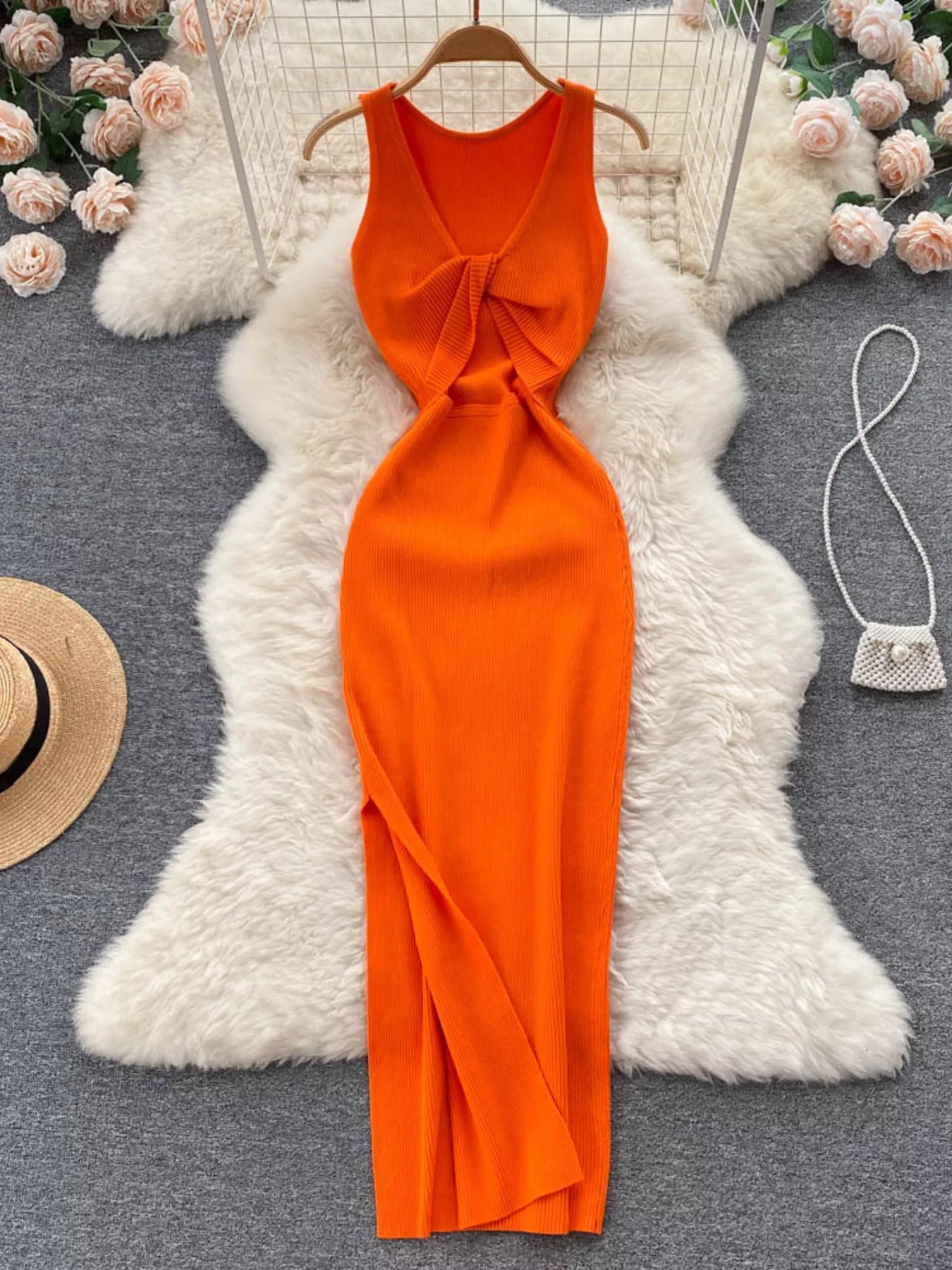 Orange sleeveless knit bodycon midi dress, back view with knotted open back on hanger
