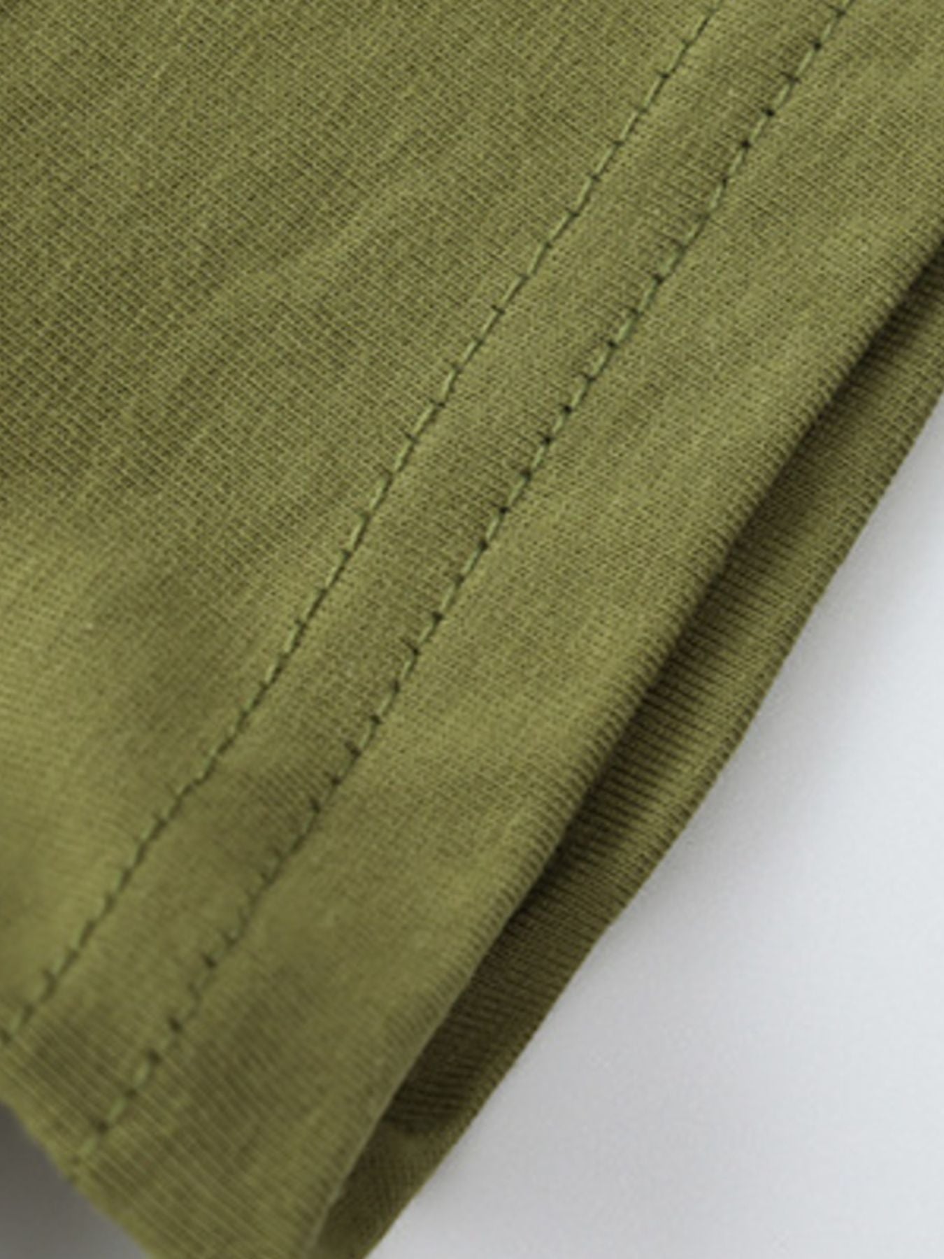 Close-up of olive children's t-shirt hem showing double stitching and smooth fabric