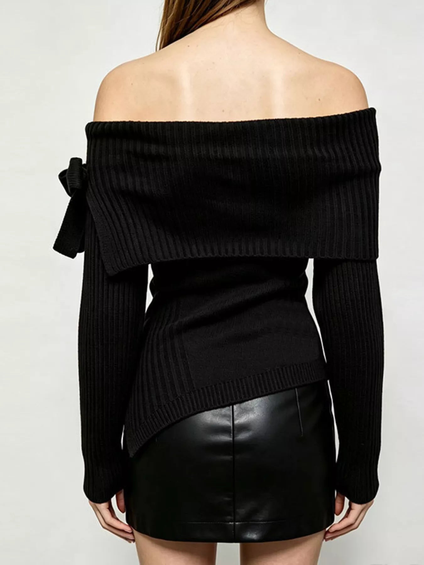 Back view of black off shoulder ribbed knit top with wide neckline and asymmetric hem