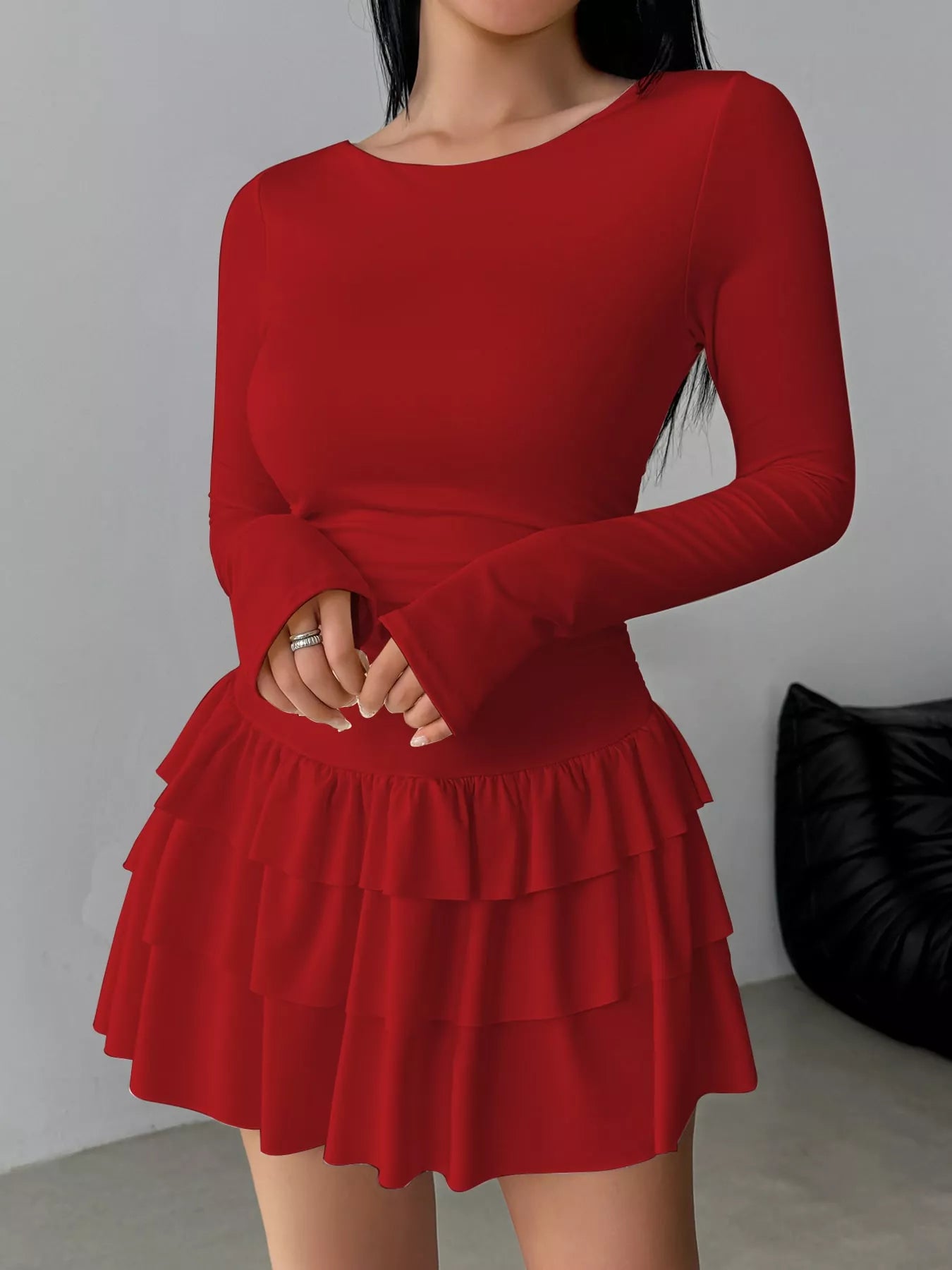 Red layered ruffle mini dress worn front facing with hands clasped at the waist