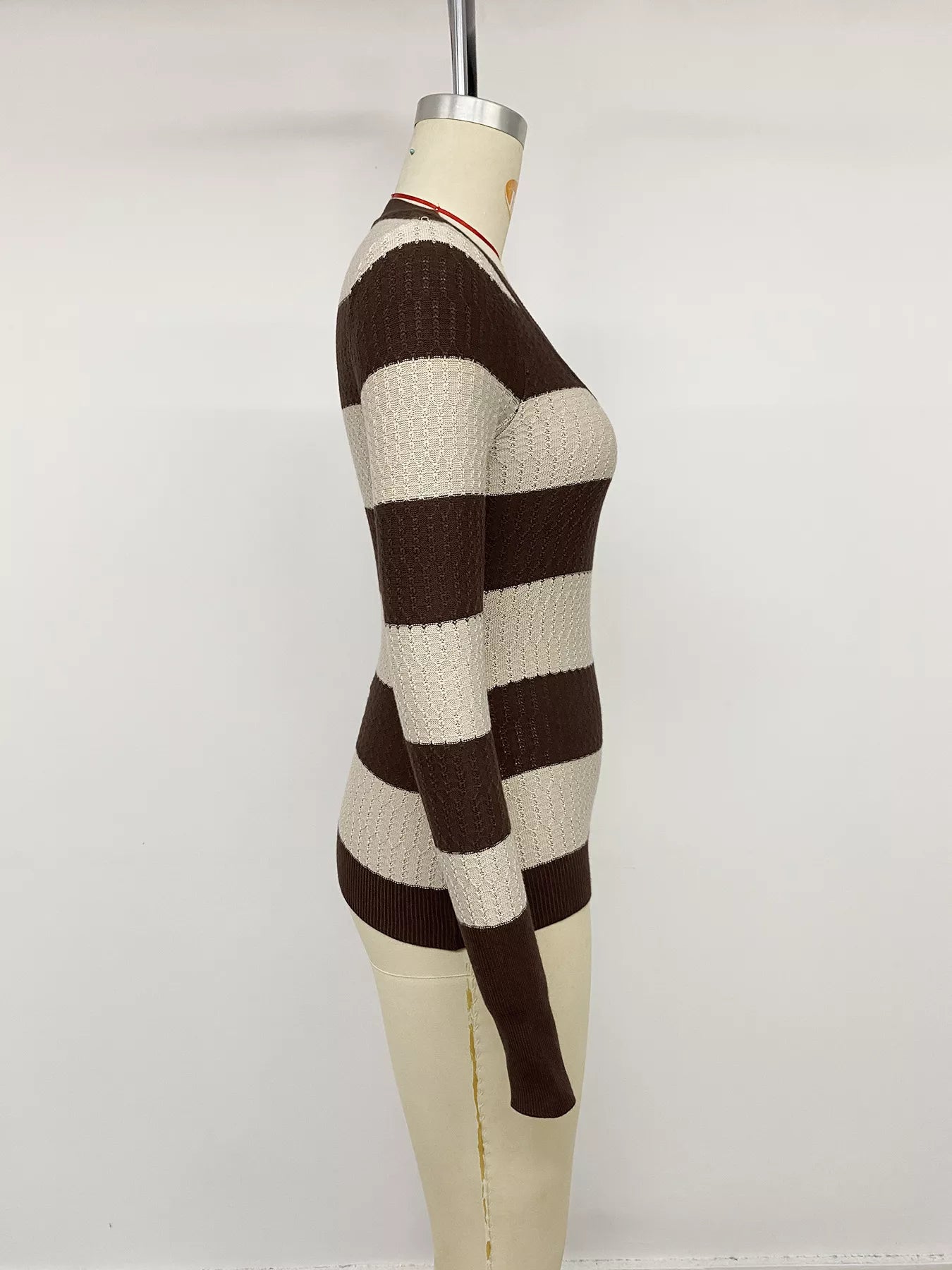 Side view of the brown and cream striped knit top on a dress form
