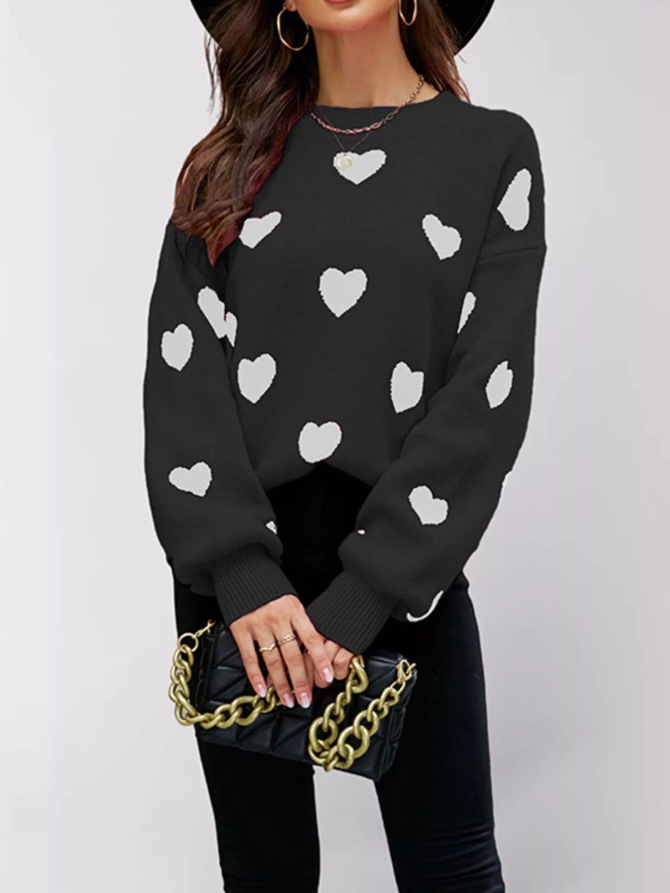 Front view of a black dropped shoulder sweater with white hearts and ribbed cuffs.