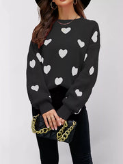 Front view of a black dropped shoulder sweater with white hearts and ribbed cuffs.